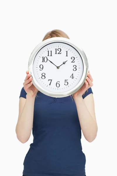 Blonde woman holding a clock in front of her face Stock Photo