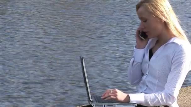 Joven mujer rubia atractiva en el ordenador portátil al aire libre — Vídeos de Stock