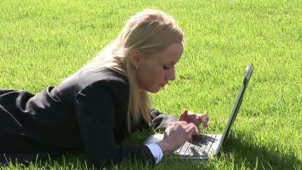 Frau liegt mit Laptop im Gras — Stockvideo