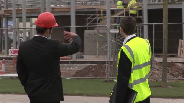 Dos ingenieros en discusión en un sitio de construcción — Vídeo de stock