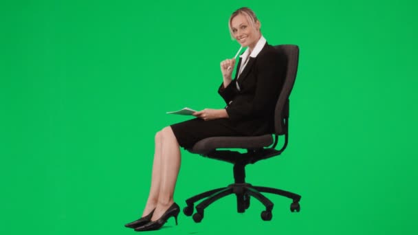 Businesswoman sitting on a chair writing notes against green screen — Stock Video