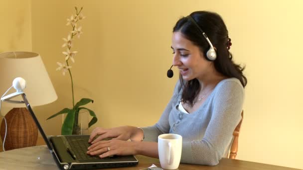 Smiling woman talking on internet with headset on — Stock Video