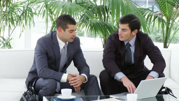 Businessmen sitting on sofa using a laptop — Stock Video