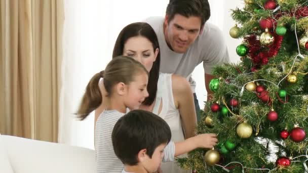 Geschwister schmücken mit ihren Eltern einen Weihnachtsbaum — Stockvideo