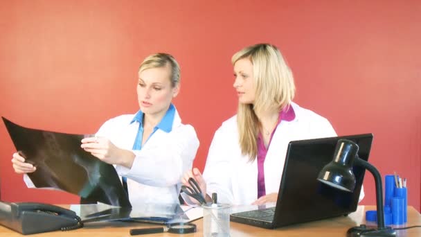 Hermosos doctores estudiando una radiografía en el consultorio — Vídeos de Stock