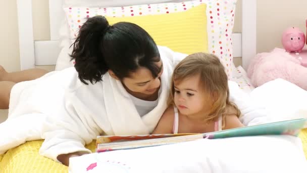 Matka, czytając książkę na jej małą córeczkę w sypialni — Wideo stockowe