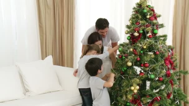 Ouders en kinderen versieren van een kerstboom — Stockvideo