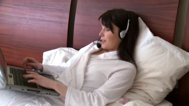 Mulher sorrindo usando um laptop com fone de ouvido em — Vídeo de Stock