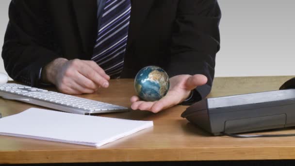 Zakenman met een roterende terrestrische globe in zijn open hand — Stockvideo