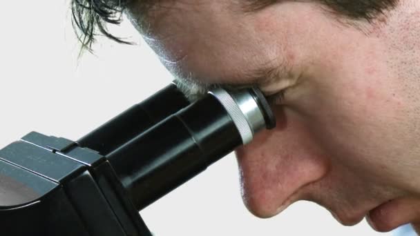 Людина дивиться в мікроскоп — стокове відео