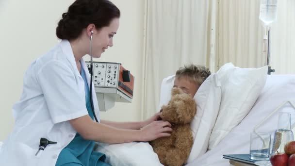 Женщина-врач разговаривает и играет с маленьким мальчиком, выздоравливающим в больнице — стоковое видео