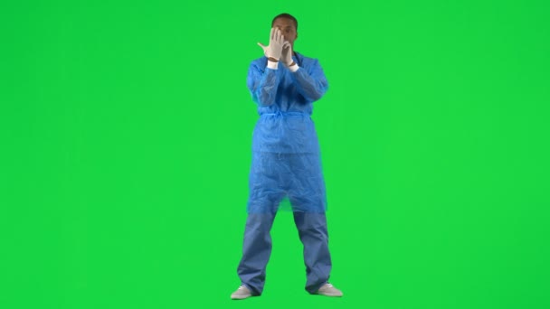 Ethnic surgeon putting on gloves against green screen — Stock Video