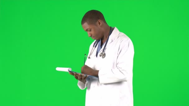 Afro-American doctor writing notes against green screen — Stock Video