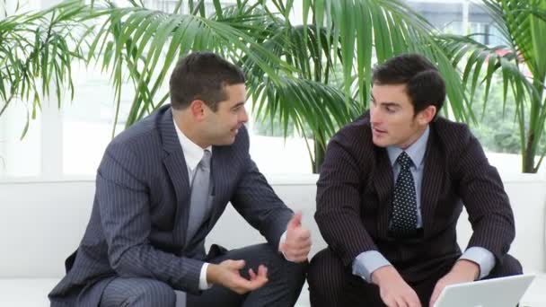 Dva podnikatelé, sedí na pohovce s notebookem — Stock video