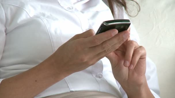 Charming woman sending a text message on the sofa Stock Video