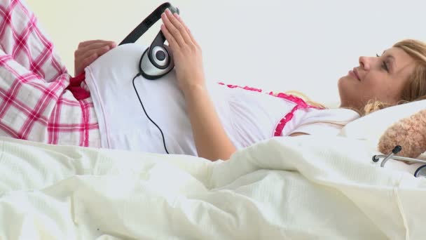Χαμογελώντας έγκυος χρησιμοποιώντας ακουστικά για την κοιλιά — Αρχείο Βίντεο