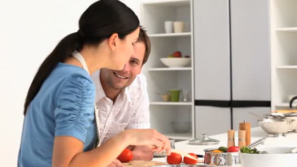 Un homme parle avec sa copine pendant qu'elle cuisine — Video