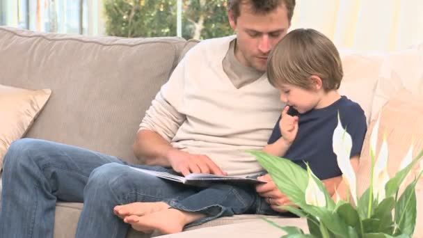 Mann liest mit seinem Sohn ein Buch — Stockvideo