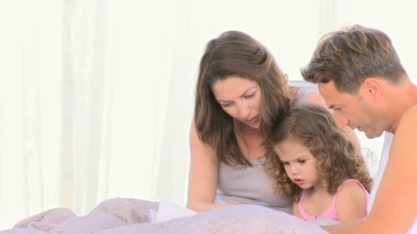 Eltern lesen ihrer Tochter ein Buch vor — Stockvideo
