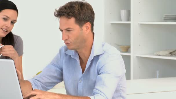 Man talking with her girlfriend while he is working on his laptop — Stock Video