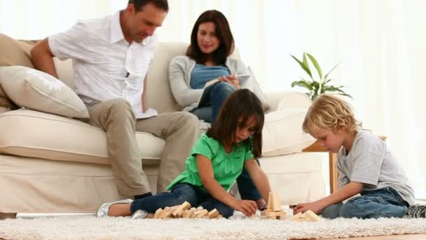 Ouders samen praten terwijl hun spelende kinderen — Stockvideo