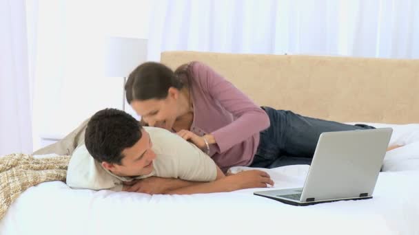 Женщина лежит на своем парне, пока он работает над своим ноутбуком — стоковое видео