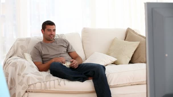 Мужчина смотрит телевизор, когда его жена приходит домой после покупок — стоковое видео