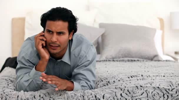 Мужчина разговаривает по телефону на кровати — стоковое видео