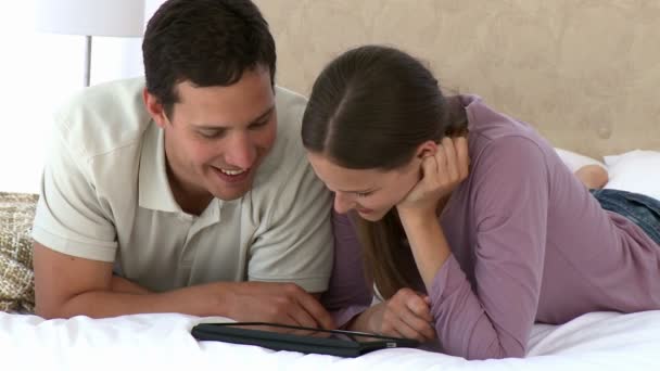 Casal feliz usando um tablet de computador sentado no sofá — Vídeo de Stock