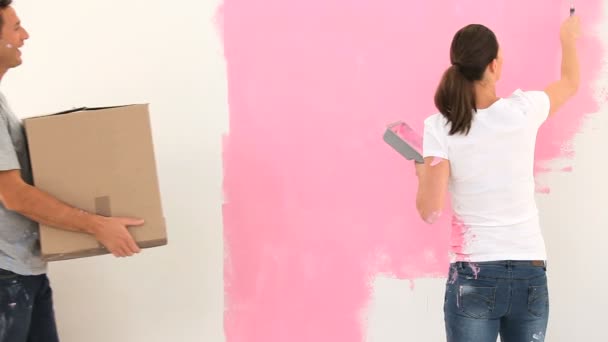 Mujer joven pintando una pared y hablando con su marido — Vídeos de Stock