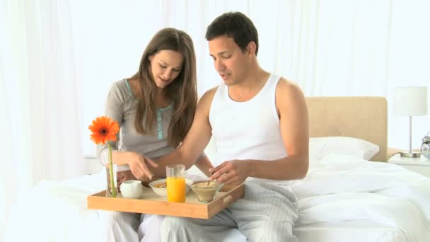 Beautiful couple having breakfast sitting on the bed — Stock Video