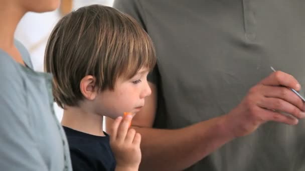 Boy eating vegetables while his father is serving the plates — Stock Video