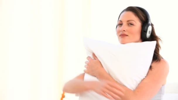 Woman hugging her pillow and listening to music — Stock Video