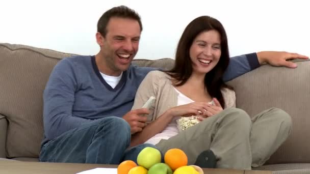 Прекрасная пара смотрит телевизор, сидя на диване — стоковое видео