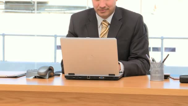 Гарненький бізнесмен працює на ноутбуці в своєму офісі — стокове відео