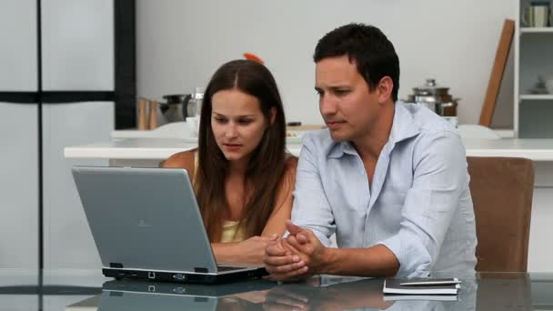 Cute couple looking at the laptop while sitting at a table — Stock Video