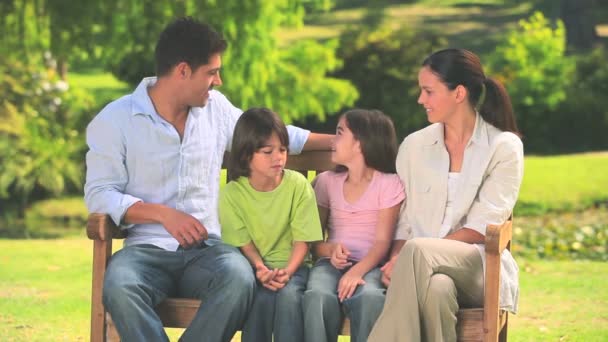 Family sitting on a park bench — Stock Video