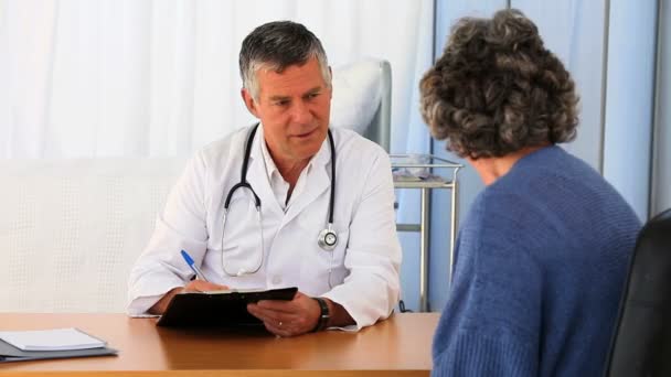 Старший врач разговаривает со своим пациентом — стоковое видео