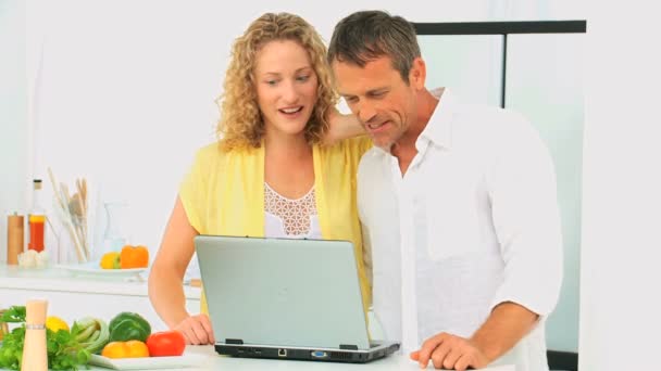 Preciosa pareja mirando una receta en un ordenador portátil — Vídeos de Stock