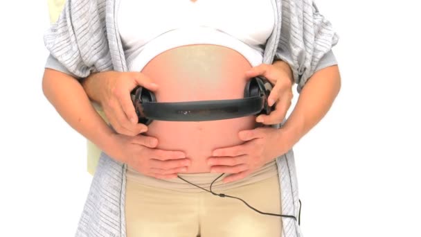 Man putting headphone on the belly of his pregnant wife — Stock Video