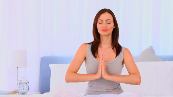 Friedliche Frau praktiziert Yoga auf ihrem Bett — Stockvideo