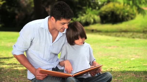 Vader en zoon vergadering lezen buitenshuis — Stockvideo