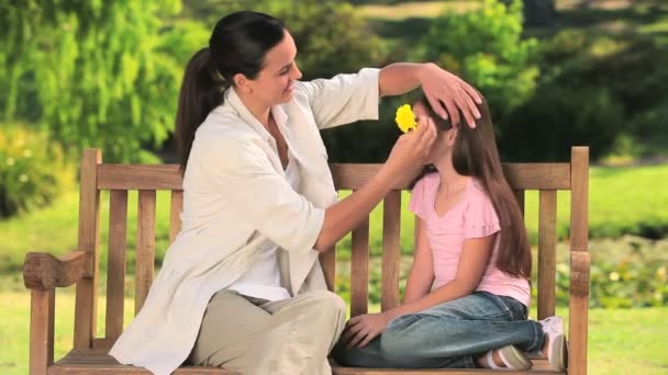 Madre poniendo una flor en el pelo de su hija — Vídeos de Stock