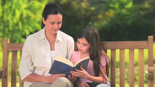 Мати і дочка читають на відкритому повітрі — стокове відео