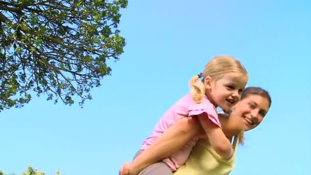 Madre che porta sua figlia sulla schiena — Video Stock