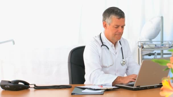 Зрелый врач работает над ноутбуком — стоковое видео