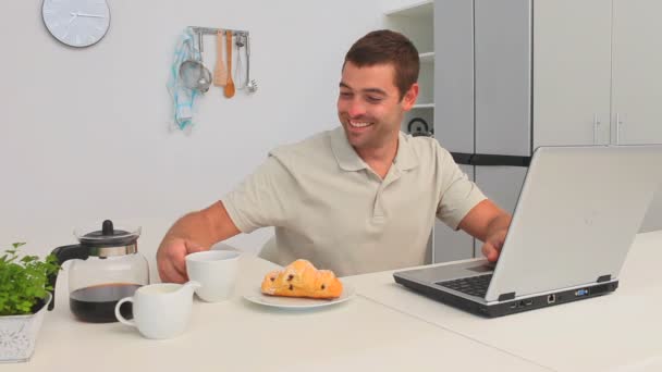 Hombre casual con un portátil desayunando — Vídeos de Stock