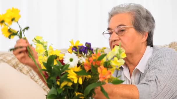 Idősebb nő, ami egy csomó virágot — Stock videók