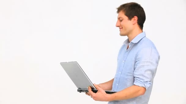 Молодой человек стоит с ноутбуком — стоковое видео