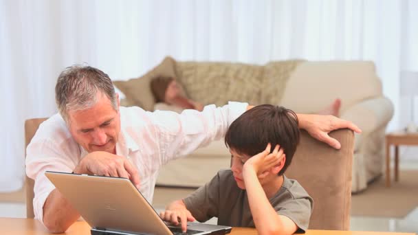 Grootvader helpen zijn kleinzoon met behulp van een laptop — Stockvideo